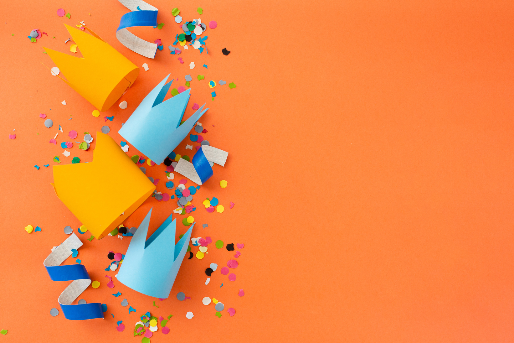 Paper Crowns and Confetti on Orange Background